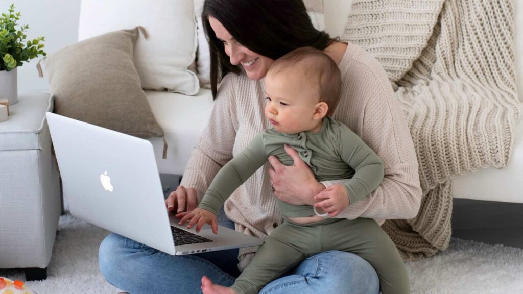 stay at home mom designing her website while holding her baby