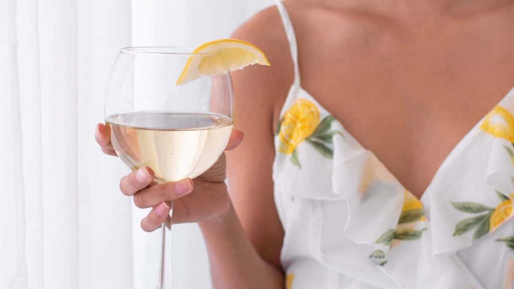woman in a sundress holding a glass of sparking wine